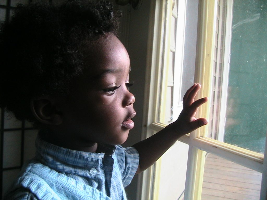 jong kind kijkt nieuwsgierig uit het raam, een kansrijke start voor een dreumes